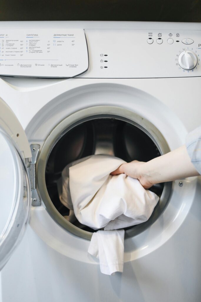 A Person Putting Clothes in a Washing Machine